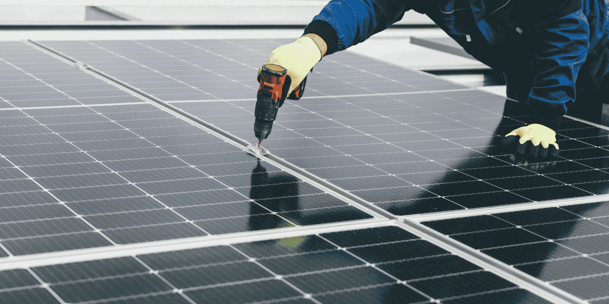 Person bei der Montage von Photovoltaikmodulen mit Akkuschrauber auf einer Solaranlage.